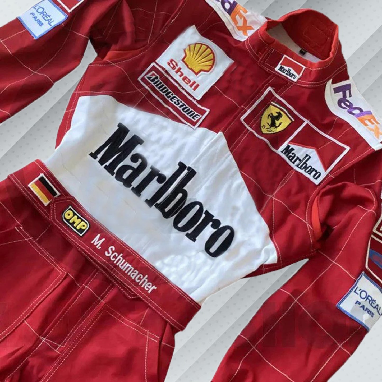 2001 Michael Schumacher F1 race suit in Ferrari's signature red, featuring prominent sponsor logos including Marlboro and Shell. The suit showcases Schumacher's name and iconic details from his dominant season, capturing the spirit of his championship-winning era with Ferrari.